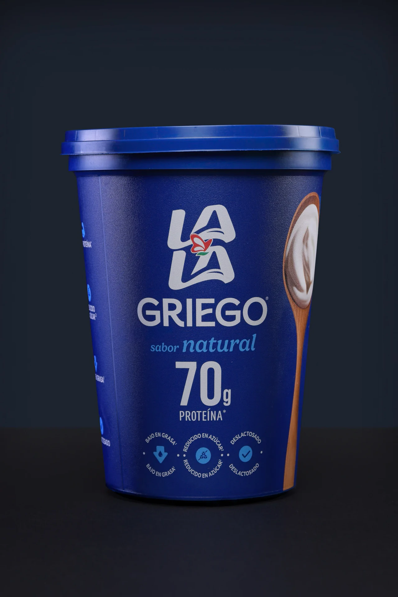 Envase de yogurt griego fotografiado como producto sobre fondo azul