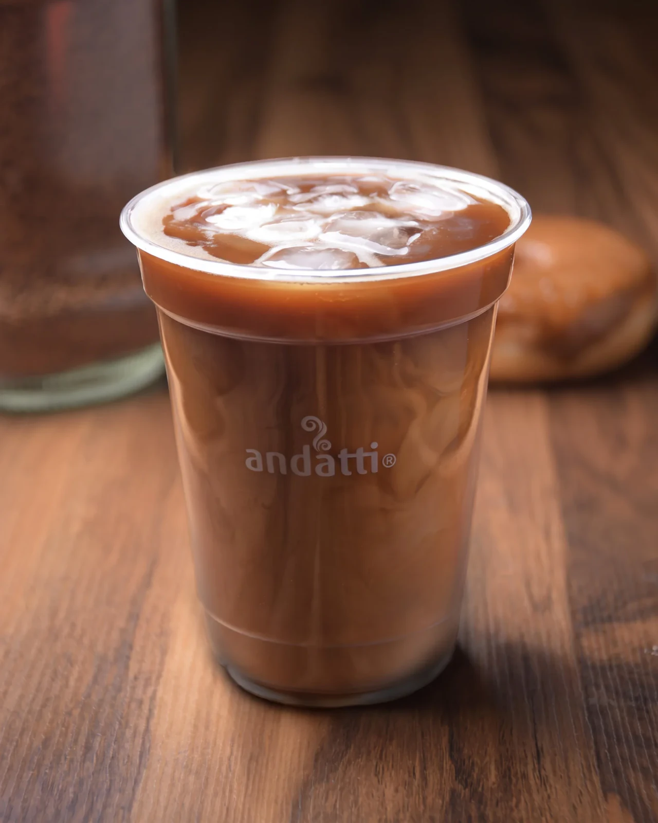 Café frío en vaso para llevar sobre mesa de madera